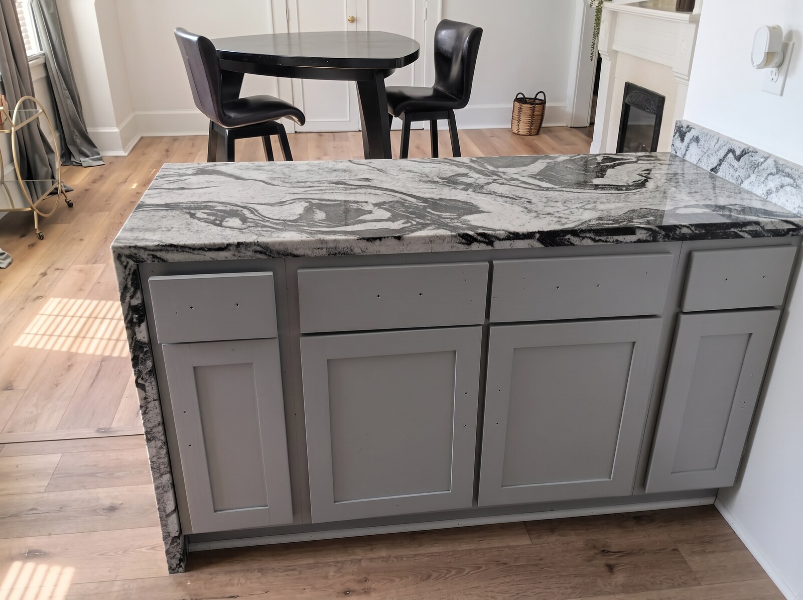 The same kitchen island painted gray, with the same veined granite countertop, after refinishing