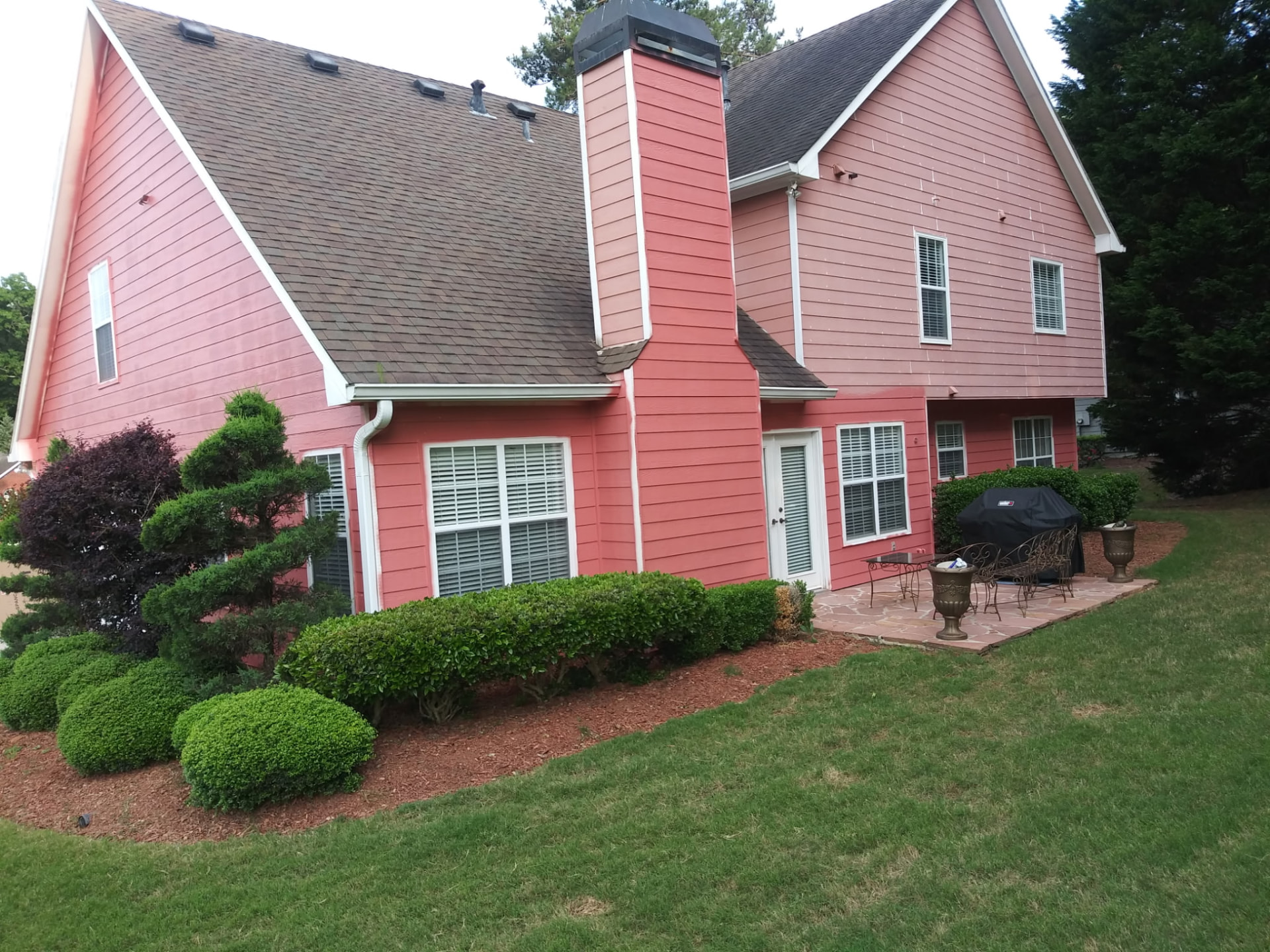 Rear view of a freshly painted two-story home with painted chimney